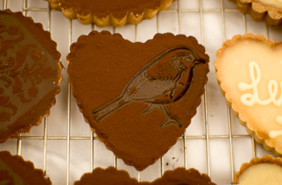Coco&Me - chocolate tart in a shape of a heart with a bird design stamped with cocoa powder